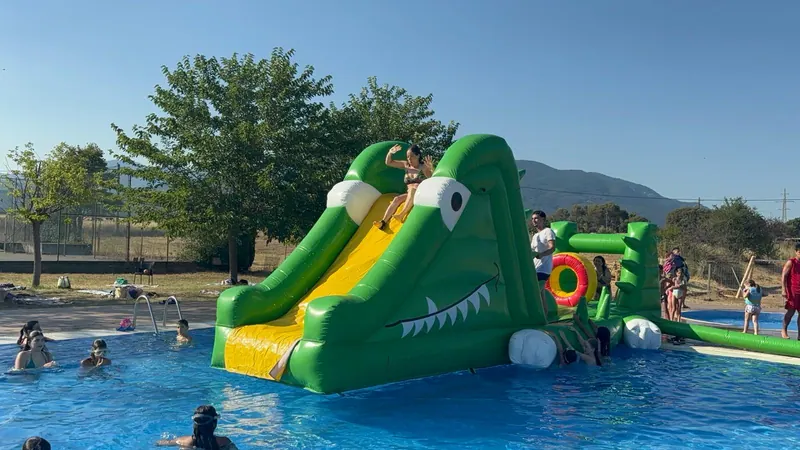 Nens i nenes jugant amb un tobogan inflable dins la piscina.