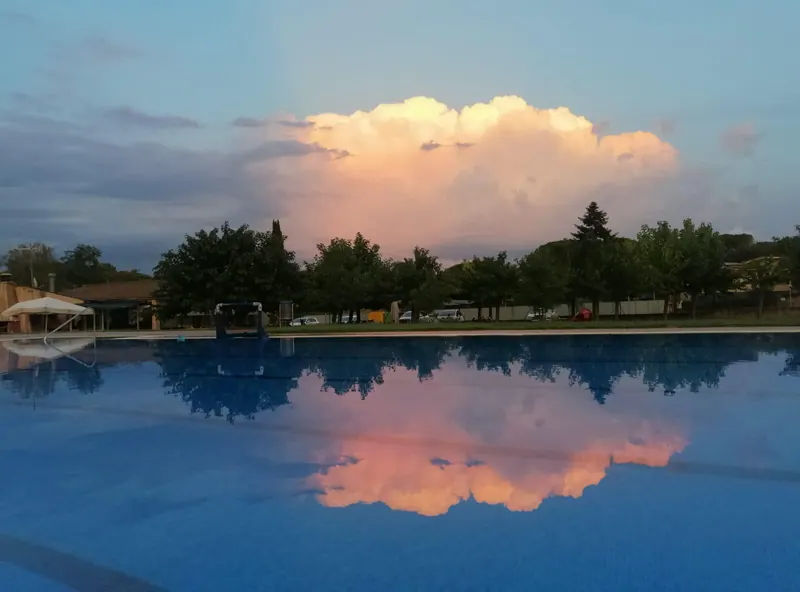 Un núvol gros de tarda reflectit a l'aigua de la piscina.
