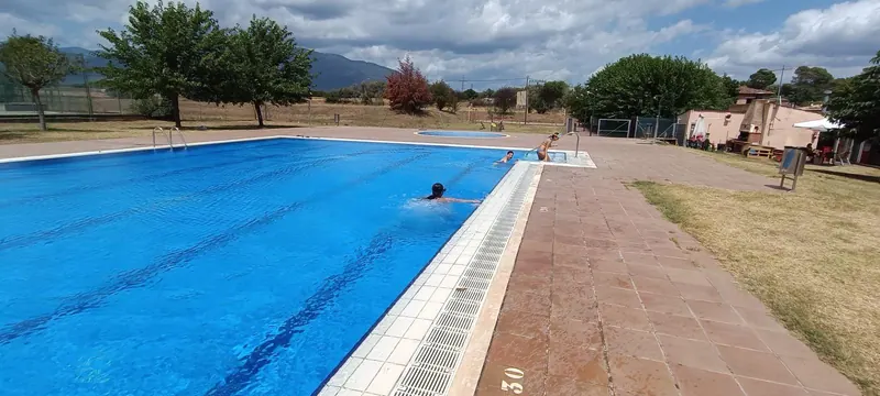 Dues persones nedant a la piscina un dia de núvols.