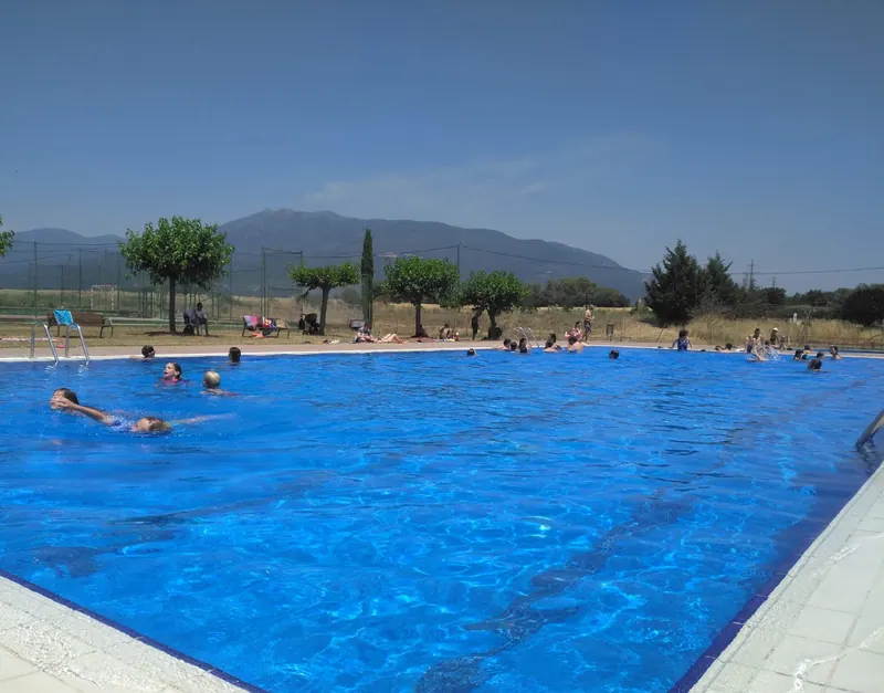 La piscina plena de gent un migdia d'estiu, amb el Montseny al fons.