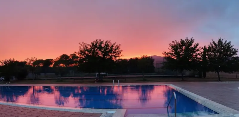 Posta de sol taronja i rosa sobre la piscina de Can Pagà.