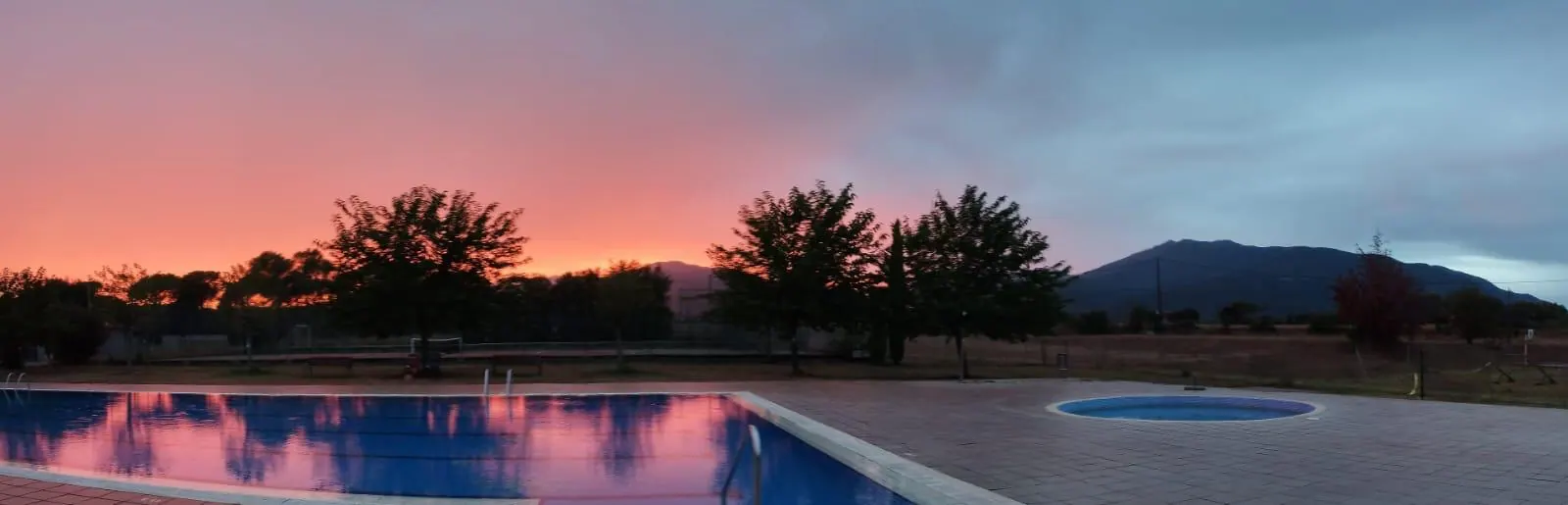 Posta de sol sobre la piscina, amb el Montseny retallat al fons.