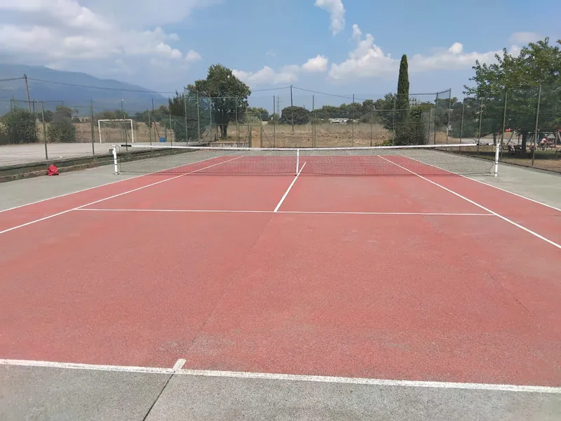 La pista de tennis de Can Pagà, amb la xarxa parada i el Montseny retallat al fons.