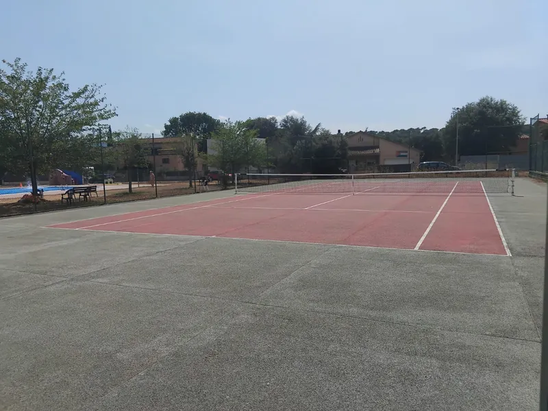 La pista de tennis amb la piscina a tocar, un matí de sol.